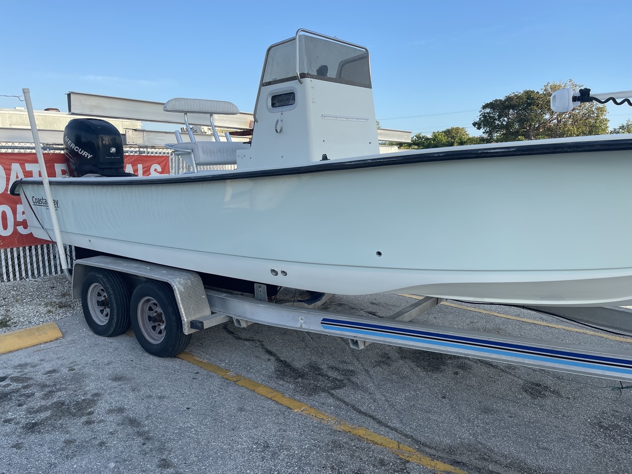 Restored white fiberglass boat on trailer with Mercury outboard engine after professional repair by Outboard Service Express